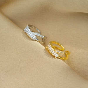 Detailed view of crossed gold and silver rings with cubic zirconia on beige fabric