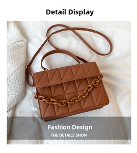 Gros plan de sac en cuir marron mat avec coutures triangulaires et chaîne décorative