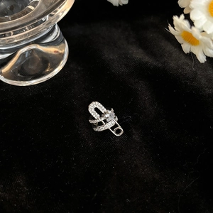 Detailed macro view of silver paperclip ear cuff with zircon inlay on black velvet surface