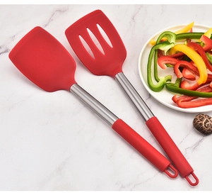 Close-up of red silicone spatulas with stainless steel handles on marble surface