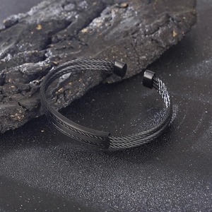 Detail of black woven stainless steel wire cuff bracelet with textured central connector