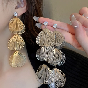 Macro detail of triple-layered leaf earrings with brushed metal and zircons