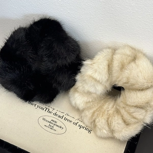 Detail of plush faux fur scrunchies in black and beige with soft fluffy texture