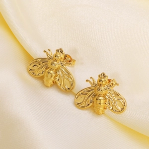 Exquisite 18k gold plated honey bee stud earrings on yellow silk fabric background