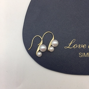 Detail of elegant gold double freshwater pearl drop earrings on a navy display pad