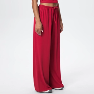 Detail of red high-waisted wide-leg trousers with drawstring waist and side pockets
