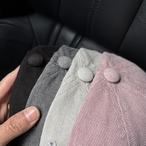 Detail of top button and fine stitching on colorful cotton twill baseball caps