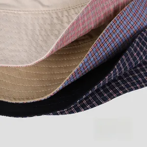 Detail of reversible cotton bucket hats showing plain beige and classic plaid patterns