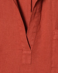 Détail du col en V et de la texture du tissu en lin rouge rouille sur cette robe longue