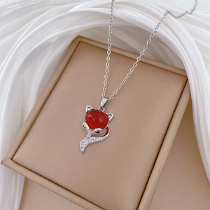 Close-up of silver fox pendant necklace with red gemstone and sparkling accents