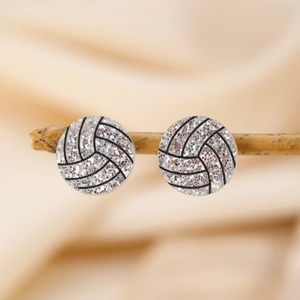 Gros plan de boucles d'oreilles volleyball rose scintillant sur une branche de bois détail