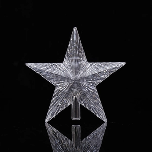Close-up of clear star tree topper with faceted surface and reflection on black background