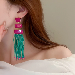 Bohemian tassel earrings with pink resin plates and green beads on a female model