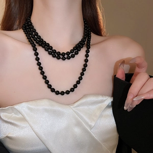 Close-up of triple-layered glossy black faux pearl necklace on model neck