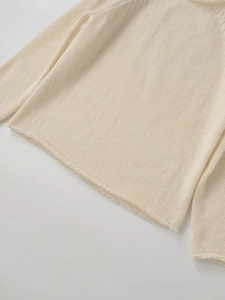 Detailaufnahme des cremefarbenen Grobstrickpullovers mit Saum im Rollrand-Design