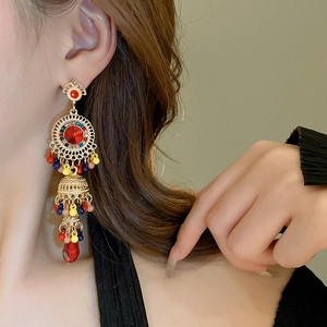 Close-up of bohemian gold tassel earrings with red rhinestones and multicolor beads