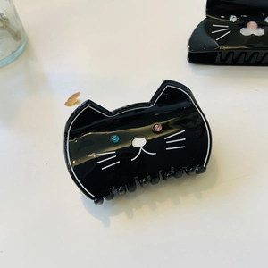 Close-up of black acetate cat hair claw with sparkling rhinestone eyes and white whiskers