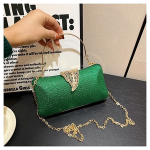 Close-up of green glitter evening clutch with golden leaf clasp and metal handle
