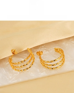 Detailed macro view of triple-layered twisted rope gold earrings on a pearl tray