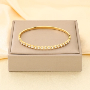 Dettaglio del bracciale rigido in acciaio dorato 18K con zirconi bianchi