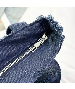 Macro shot of silver metal zipper detail on frayed edge dark blue denim tote bag