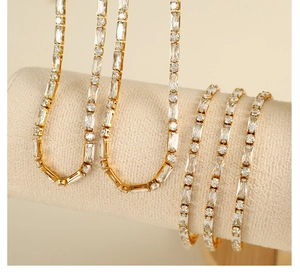 Detail of gold tennis necklace with alternating round and baguette zirconia stones