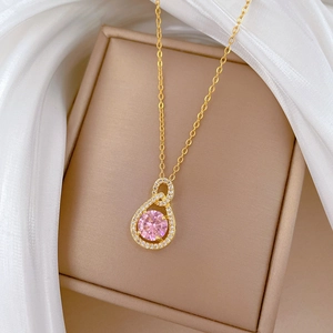 Detailed close-up of a pear-shaped pink crystal necklace on elegant silk fabric