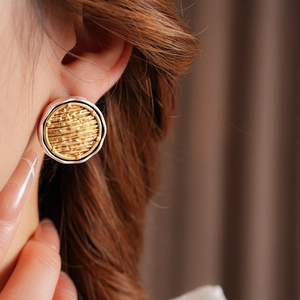 Close-up of minimalist round mixed-metal earrings with gold texture and silver borders