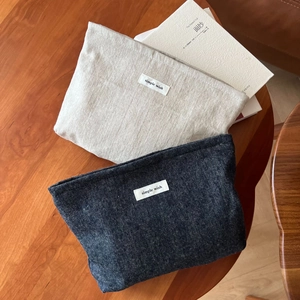 Detail of beige cotton and blue denim makeup bags with simple wish labels on wood