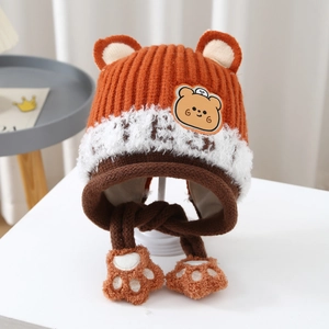 Close-up of children's knit earflap hat featuring bear ears and cute paw-shaped tassels