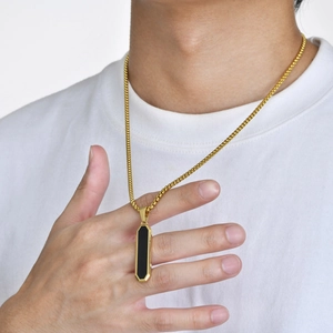 Close-up of a men's geometric black bar pendant with gold trim on a white T-shirt