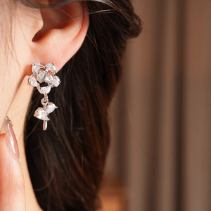 Gros plan de boucles d'oreilles fleur en argent avec zircons portées par un mannequin