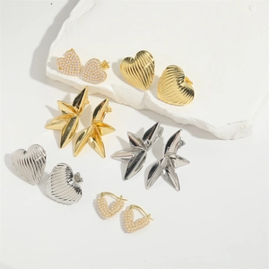 Detailed view of textured gold and silver heart earrings with pearl accents on stone