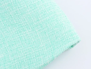 Gros plan sur la texture du tissu en tweed vert menthe d'un gilet élégant pour femme