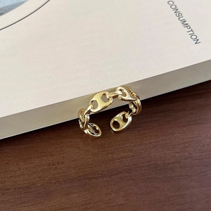 Detail of adjustable gold-finished chain ring on a wooden surface and vintage book