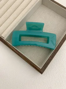 Detail of teal rectangular hair claw clip in a jewelry tray with beige fabric lining