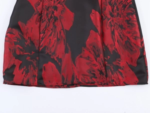 Gros plan sur le tissu jacquard noir et rouge au bas de la robe avec motif floral