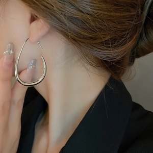 Close-up of a silver teardrop earring on model with a minimalist streamlined design