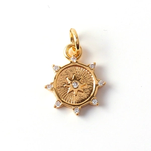 Detailed close-up of a gold-plated circular pendant with a star pattern and clear gems
