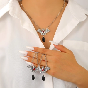 Close-up of gothic silver bat necklace and earring set with red and black stones