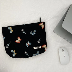 Detail view of black canvas makeup bag with butterfly embroidery and smooth zipper closure