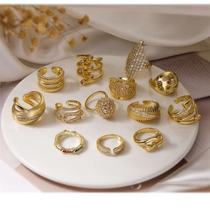 Elegant gold-tone open rings collection with zircon stones on silk and newspaper background