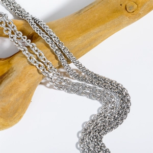 Close-up of vintage titanium steel necklaces with woven texture on a wooden background