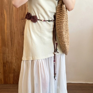 Detail of fabric rose waist belt with wooden beads on a beige chiffon floral dress