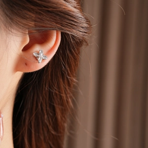 Gros plan d'une boucle d'oreille fleur argentée avec zircons portée par un mannequin