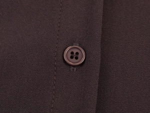 Macro view of dark brown fabric texture and matching four-hole resin buttons detail