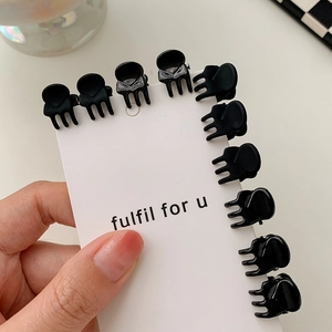 Detailed view of ten mini black hair clips secured on a white display card