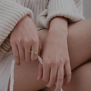 Detail of 18K gold-plated hammered ring with green gemstone on model hand