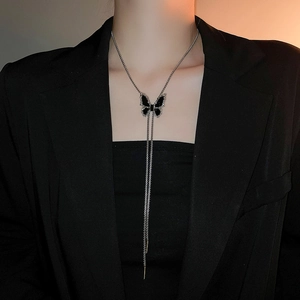 Elegant long chain necklace with butterfly pendant and tassels on a model in a black suit