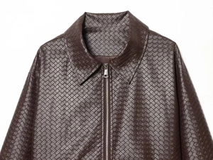 Macro shot of dark brown woven leather texture on a lapel jacket with metal zipper
